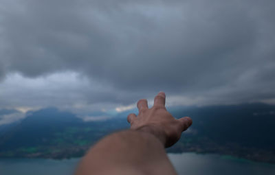 Close-up of woman hand against mountain against sky