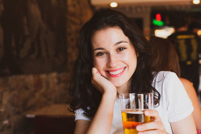 Close-up portrait of young woman holding beer in restaurant