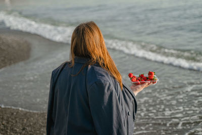 Rear view of woman standing at beach