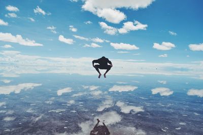 Silhouette of man jumping over reflections on salt flats in bolivia.