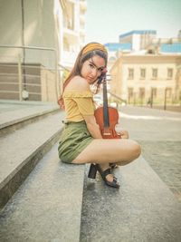 Portrait of woman holding umbrella in city