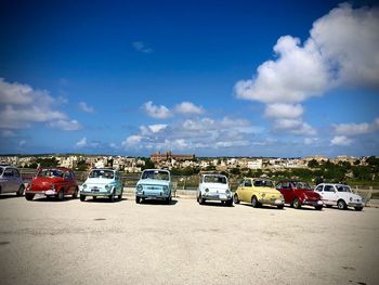 Row of cars parked on road against blue sky