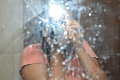 Midsection of woman holding glass of water