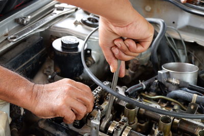 Cropped hands of mechanic repairing car engine