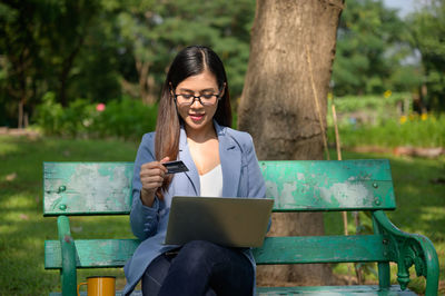 Young woman using phone while sitting on bench