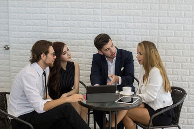 Business colleagues discussing while sitting at table in office