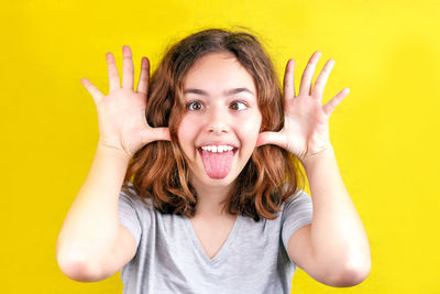 Portrait of happy young woman against yellow background