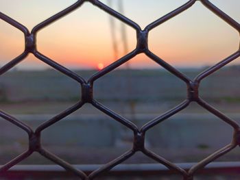 Full frame shot of chainlink fence against sky during sunset