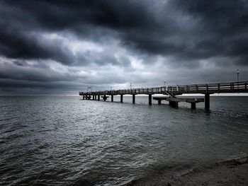 Bridge over sea against cloudy sky