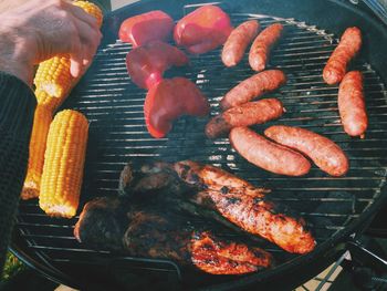 Cropped hand grilling food on barbecue