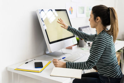 Creative businesswoman touching computer screen while working in office