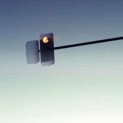 Low angle view of road signal against clear blue sky