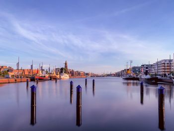 Boats moored at harbor against blue sky