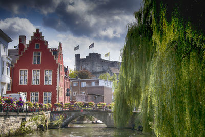 Arch bridge over river amidst buildings against sky