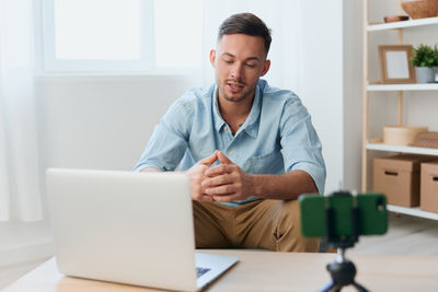 Portrait of young man using laptop at home