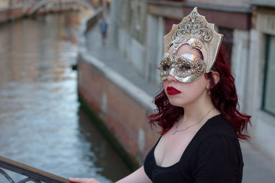 Close-up portrait of woman wearing eye mask against canal