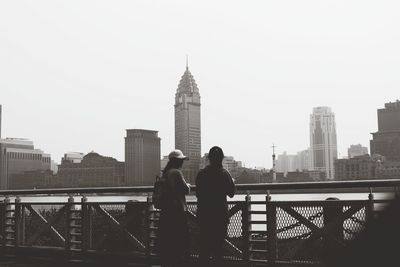 People standing on railing against buildings in city