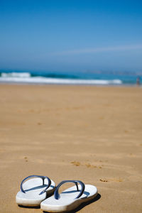 Close-up of heart shape on sand at beach against sky