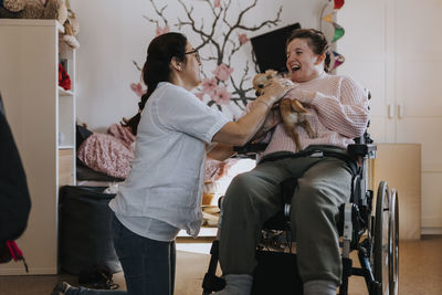 Mother with daughter on wheelchair in living room