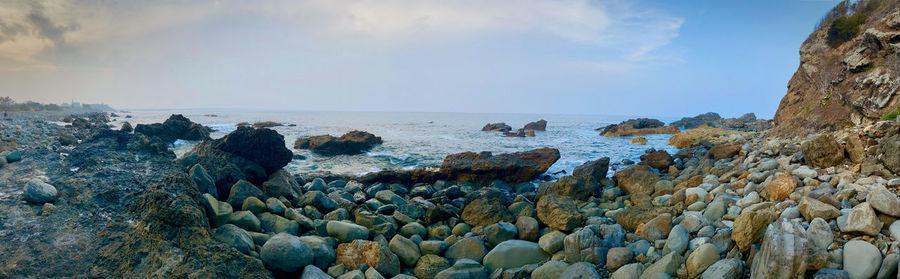 Panoramic view of rocks on beach against sky