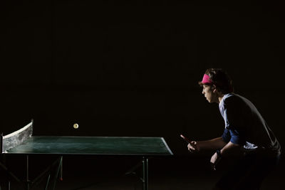 Man playing table tennis against black background