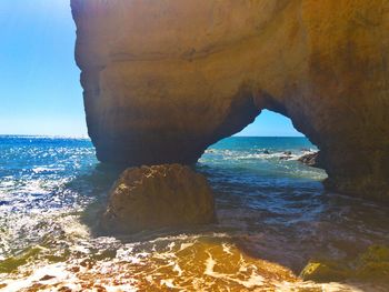 Rock formation on beach against sky