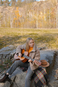 Portrait of young woman sitting on rock