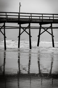 Wet pier by sea against sky during rainy season