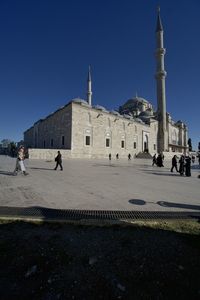 People walking in temple against clear blue sky