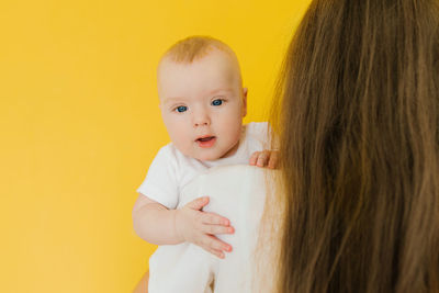 Baby boy in mom's arms on a yellow background