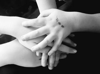 Cropped image of friends stacking hands on table