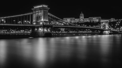 Illuminated bridge over river at night