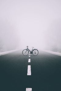 Bicycle parked on road during foggy weather