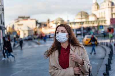 Woman wearing mask looking away standing on street