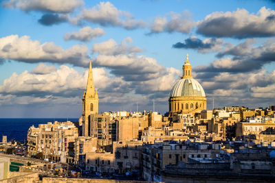 View of buildings in city against cloudy sky