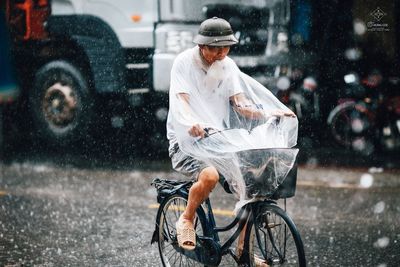 Man riding bicycle on road in rain