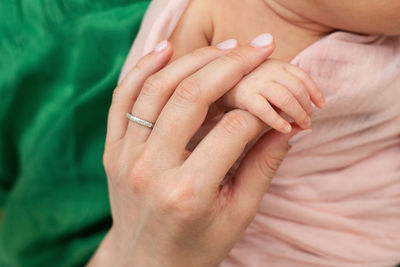 Cropped hand of mother holding baby hand outdoors