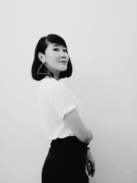 Portrait of young woman standing against white background