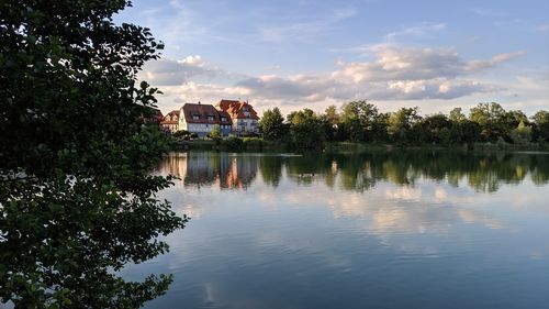 Scenic view of lake by trees and buildings against sky