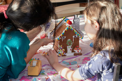 Mom and daughter making a gingerbread house on christmas day