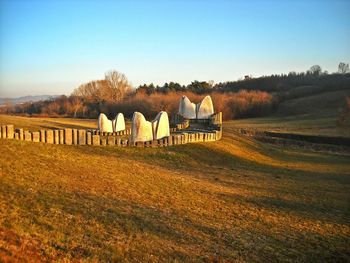 Hay bales on field against clear sky