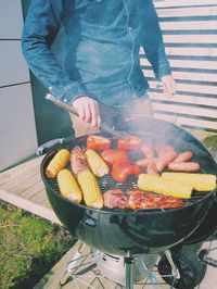 Midsection of man cooking food on barbeque grill