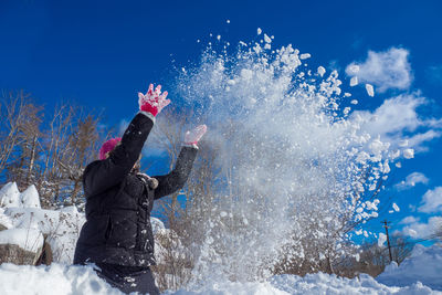 Girl flinging snow in winter