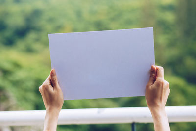 Close-up of hand holding paper against blurred background