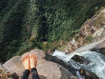 Low section of person standing by waterfall