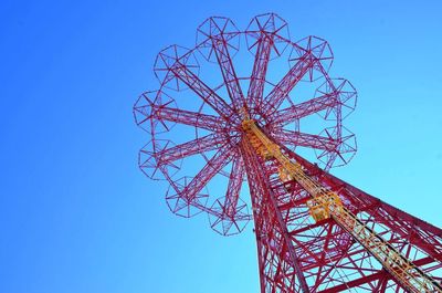 Low angle view of rollercoaster against clear blue sky