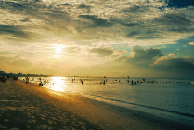 People on beach against sky during sunset