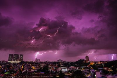 Lightning over illuminated buildings in city at night