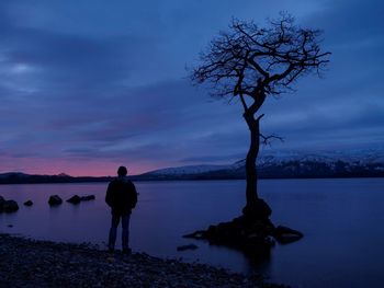 Silhouette of person standing at lakeside