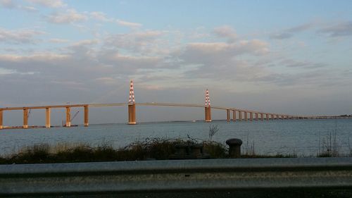 Bridge over sea against cloudy sky